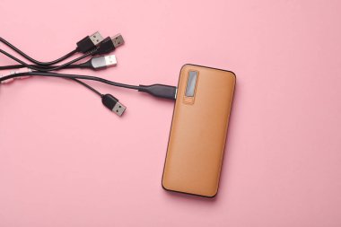 Pembe arka planda birçok usb kablosu olan dış batarya güç bankası