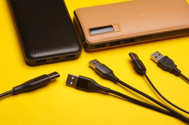 Sarı arka planda USB kablosu olan iki dış güç bankası pili..