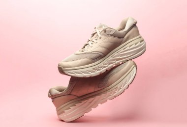 Pembe arka planda yüzen spor ayakkabıları.
