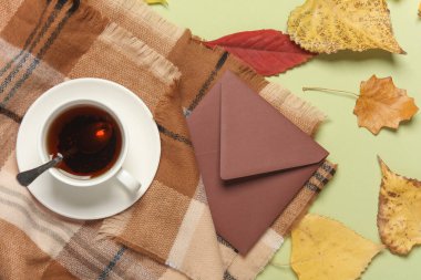 Bir fincan çay, üzerinde zarf ve sonbahar yaprakları olan battaniye. Düz yatıyordu