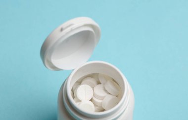 Mavi arka planda plastik hap kavanozu