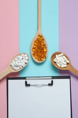 Ahşap kaşıklarda haplar ve renkli arka planda pano.