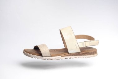 Beyaz arka planda süzülen deri sandalet