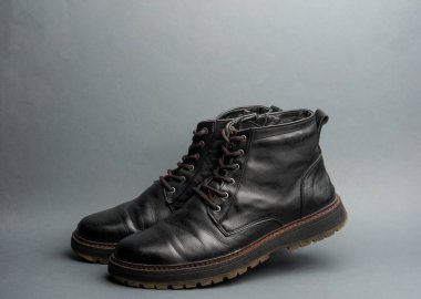 Koyu gri arka planda siyah deri erkek çizmesi.