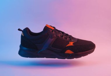 Kırmızı neon ışıkta yüzen spor ayakkabı.