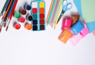 Beyaz arka planda çocukların yaratıcılığı. Boya, renkli kalemler, plastik, fırça ve makas. Düz yatıyordu. Üst görünüm