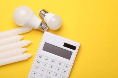 Alternatif aydınlatma, tasarruf. Sarı zemin üzerinde mum ve kurşun lamba ile hesap makinesi