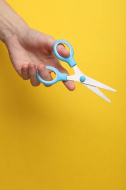Sarı arka planda yaratıcılık için el ele tutuşan makas