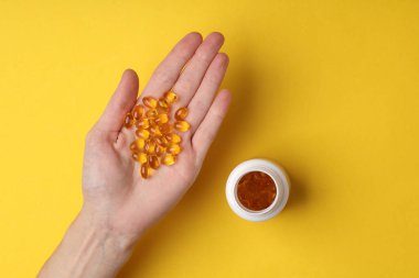 Sarı arka planda balık yağı kapsülleri.