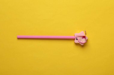 Sarı arka planda sivri uçlu pembe kalem.