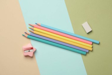 Renkli pastel arka planda silgi ve açacağı olan renkli kalemler.