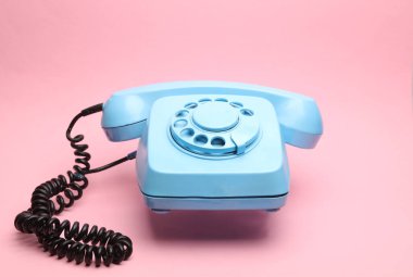 Pembe arka planda yüzen mavi eski bir telefon