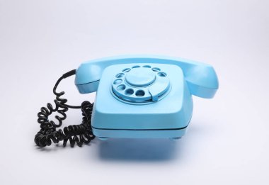 Beyaz arkaplanda yüzen mavi retro döner telefon