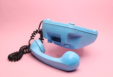 Pembe arka planda yüzen mavi eski bir telefon