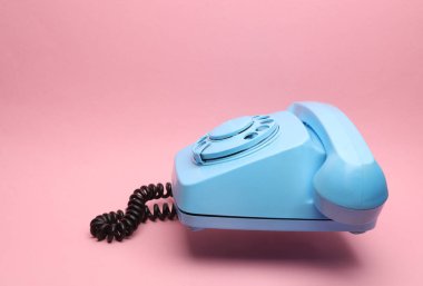 Pembe arka planda yüzen mavi eski bir telefon