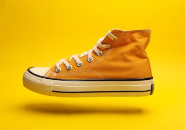 Sarı arka planda yüzen eski moda lastik ayakkabı.