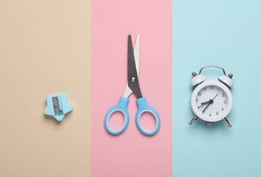 Keskinleştirici ve makas, mavi pembe alarmlı saat. Okul malzemeleri.