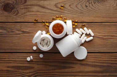 Tahta masadaki beyaz plastik şişelerde farklı tipte haplar. en üstteki görünüm