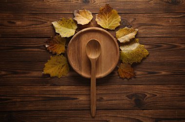 Kaşık ve sonbahar yapraklı ahşap bir tabak. Üst görünüm