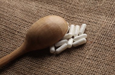 Çuval bezi arka planında tahta kaşıklı haplar.