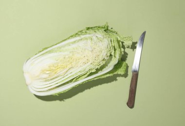 Yeşil arka planda bıçak olan Çin lahanasının yarısı. Yemek yapmak, sağlıklı yemek yemek.