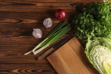 Taze yeşillik, mutfak tahtalı sebzeler ve tahta arka planda bıçak. Sağlıklı yiyecekler, vejetaryenler. Düz yatıyordu