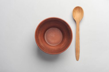 Gri arka planda tahta kaşıkla kil kase. Üst görünüm