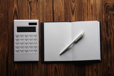 Tahta bir arka planda hesap makinesi ve defter. İş konsepti. Düz yatıyordu