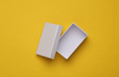 Sarı arkaplanda beyaz, boş karton kutuyu aç