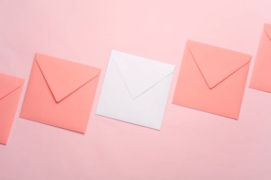Kare kağıt pembe ve beyaz zarflar pembe arka planda