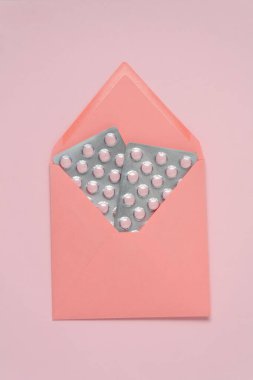 Pembe zemin üzerinde tablet kabarcıkları olan zarf