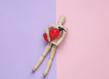 Oyuncak söndürücüyü pastel arka planda tutan tahta kukla. Üst görünüm