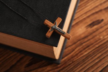 İncil kitabı ve ahşap Hristiyan haçı bir ipin üzerinde, ahşap masa