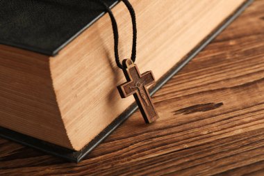 İncil kitabı ve ahşap Hristiyan haçı bir ipin üzerinde, ahşap masa