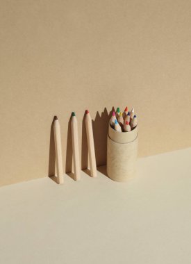 Bej bir arka planda, gölgeli ahşap renkli kalemler.