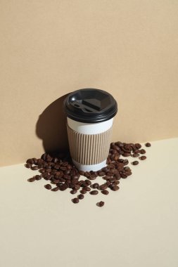 Sıcak içecekler için karton bardak ve gölgeli bej arka planda kahve çekirdeği.