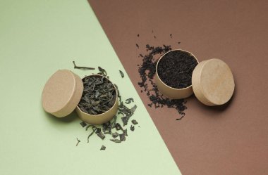 Yeşil ve siyah çay yaprakları yeşil kahverengi arka plandaki karton yuvarlak kutularda