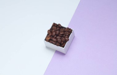 Pastel arka planda beyaz karton kutuda kahve çekirdekleri.