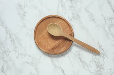 Tahta tabak ve kaşık mermer arka planda.