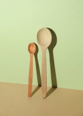 Renkli pastel arka planda ahşap kaşıklar ve gölgeler.