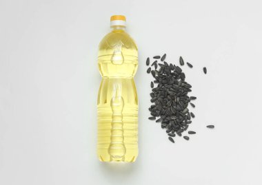 Ayçiçeği tohumları ve beyaz arka planda bir şişe yağ.