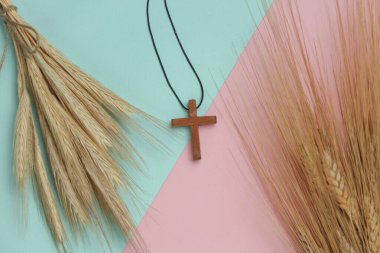 Buğday dikenleri ve ahşap bir Hristiyan haçı. Mavi pembe arkaplan