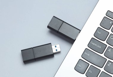 İki siyah USB flaş bellek ve klavye grisi arka plan. Üst görünüm