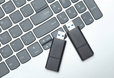 İki siyah USB flaş bellek ve klavye grisi arka plan. Üst görünüm