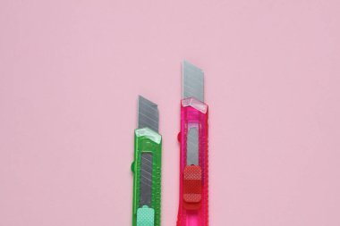 Pembe arka planda kağıt kesmek için plastik renkli kırtasiye bıçakları