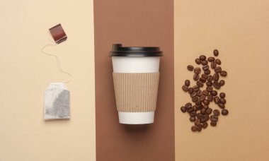 Sıcak içecekler ve kahve çekirdekleri için tek kullanımlık karton bardak bej kahverengi arka planda çay poşeti. Düz yatıyordu