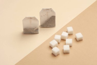 Bej kahverengi arka planda çay poşetleri ve şeker küpleri