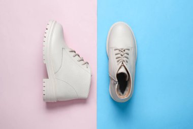 Mavi-pembe arka planda beyaz kadın deri çizmeleri. Üst görünüm