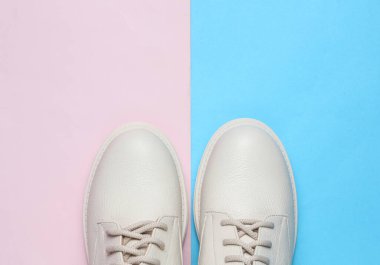 Mavi-pembe arka planda beyaz kadın deri çizmeleri. Üst görünüm