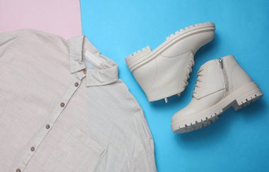 Mavi-pembe arka planda gömleği olan beyaz kadın deri çizmeleri. Üst görünüm